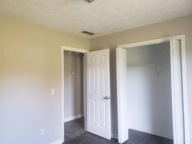 unfurnished bedroom featuring a textured ceiling and a closet