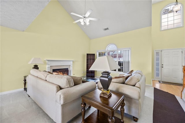 living room featuring ceiling fan, light hardwood / wood-style flooring, high vaulted ceiling, and a healthy amount of sunlight