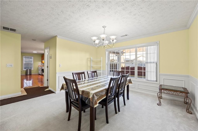 carpeted dining space with crown molding, a textured ceiling, and a chandelier