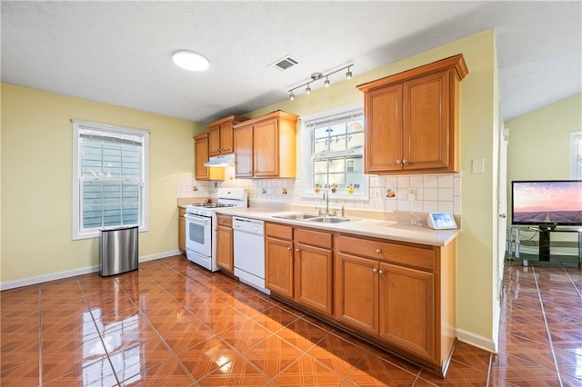 kitchen with decorative backsplash, white appliances, track lighting, and sink