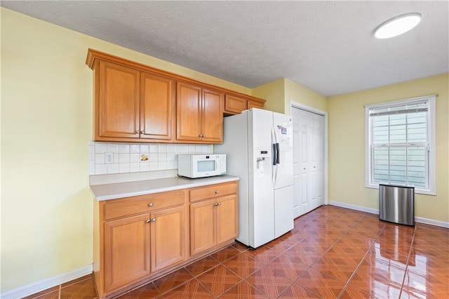 kitchen featuring white appliances, a textured ceiling, and tasteful backsplash