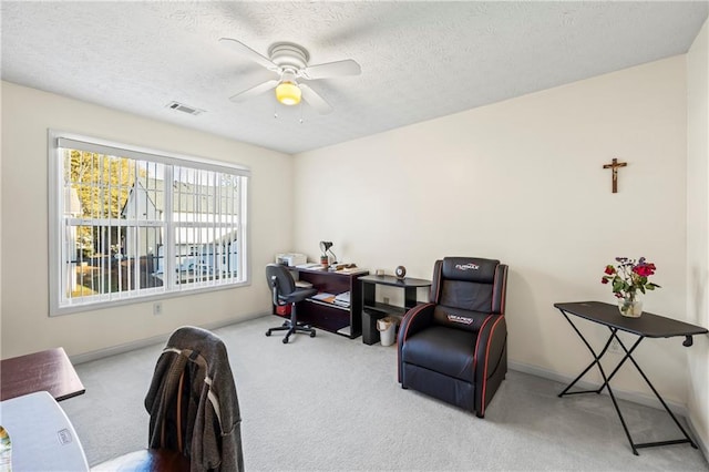 carpeted office space with a textured ceiling and ceiling fan