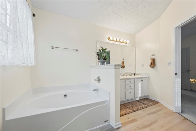 bathroom with vanity, a bath, wood-type flooring, and a textured ceiling