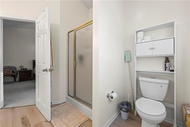 bathroom with wood-type flooring, toilet, and a shower with shower door