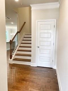 stairs with crown molding, wood finished floors, and baseboards