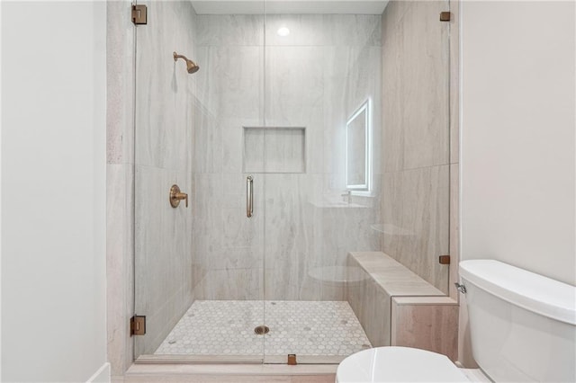 bathroom featuring a shower with door and toilet