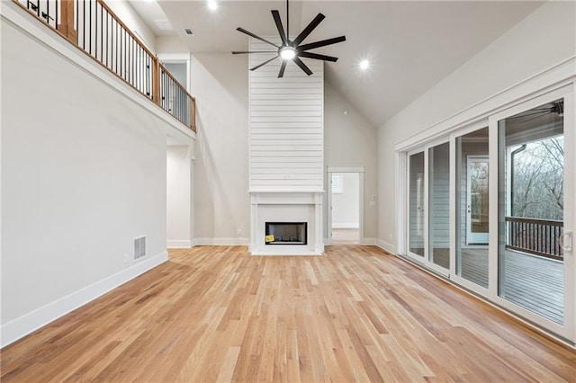 unfurnished living room featuring ceiling fan, a fireplace, high vaulted ceiling, and light wood-type flooring