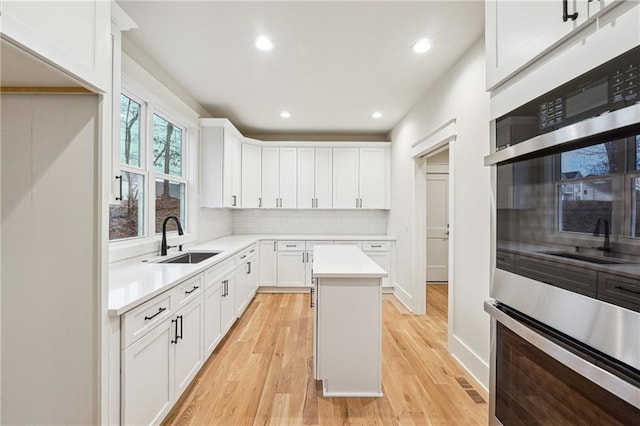 kitchen featuring tasteful backsplash, sink, white cabinets, a center island, and stainless steel double oven