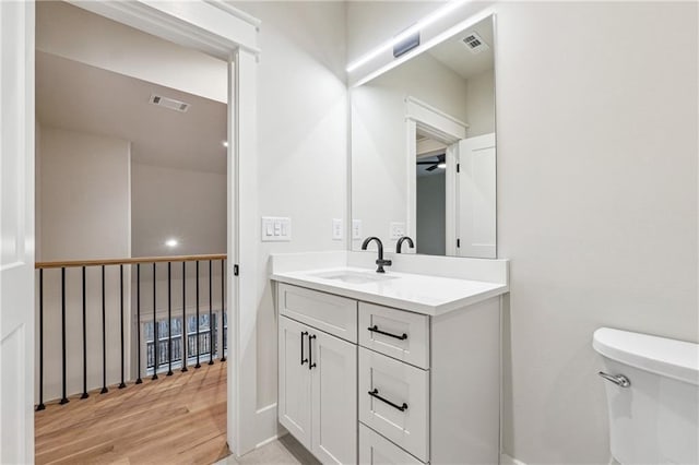 bathroom featuring wood-type flooring, vanity, and toilet