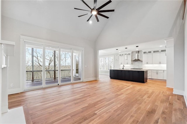 unfurnished living room featuring ceiling fan, sink, high vaulted ceiling, and light wood-type flooring