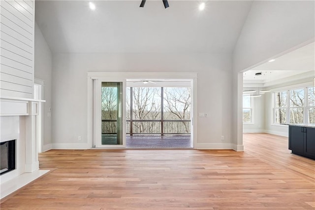 unfurnished living room with high vaulted ceiling, light hardwood / wood-style floors, and ceiling fan