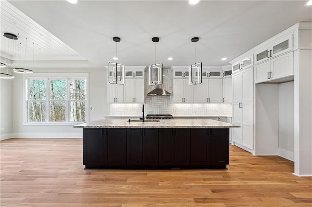 kitchen featuring a center island with sink and white cabinets