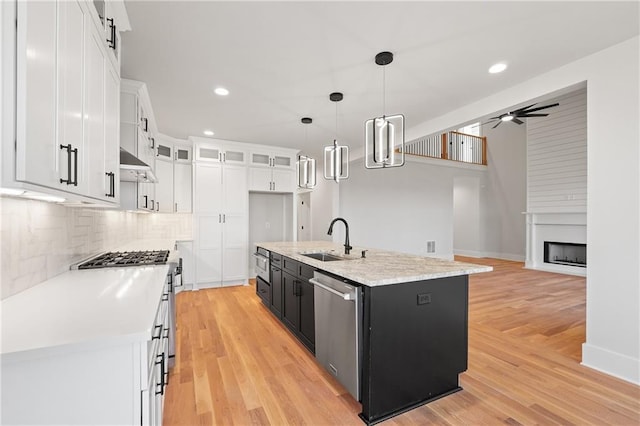 kitchen with sink, pendant lighting, ceiling fan, a kitchen island with sink, and white cabinets