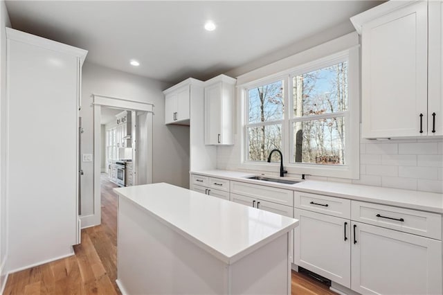 kitchen with white cabinetry, sink, high end range, and a kitchen island