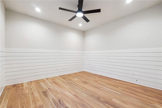 spare room featuring hardwood / wood-style flooring, ceiling fan, and wood walls