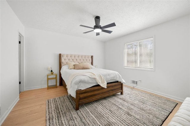 bedroom featuring ceiling fan, light hardwood / wood-style flooring, and a textured ceiling