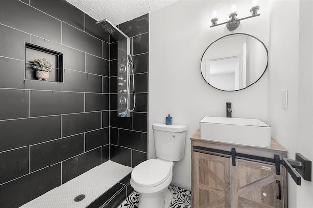 bathroom featuring tiled shower, vanity, toilet, and a textured ceiling