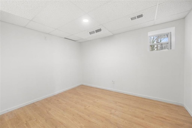 empty room featuring light hardwood / wood-style flooring and a drop ceiling