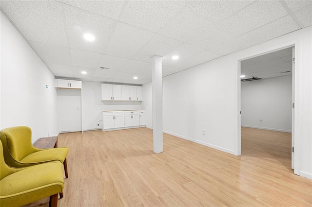 basement featuring a paneled ceiling and light wood-type flooring