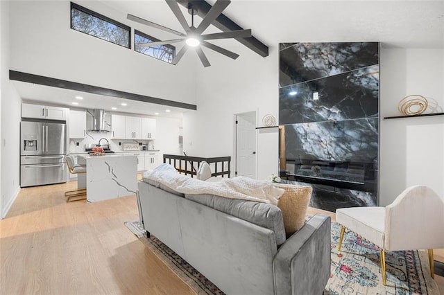 living room with sink, light hardwood / wood-style flooring, ceiling fan, and a high ceiling