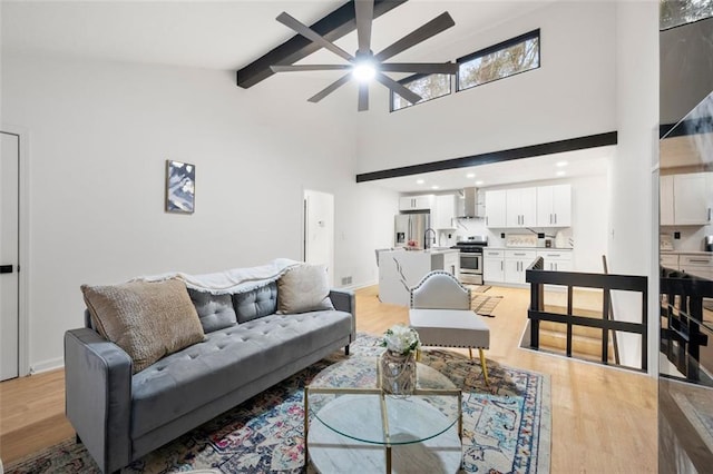 living room featuring ceiling fan, high vaulted ceiling, beam ceiling, and light hardwood / wood-style flooring