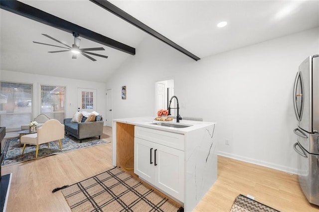 kitchen with stainless steel refrigerator, white cabinetry, sink, vaulted ceiling with beams, and light hardwood / wood-style flooring