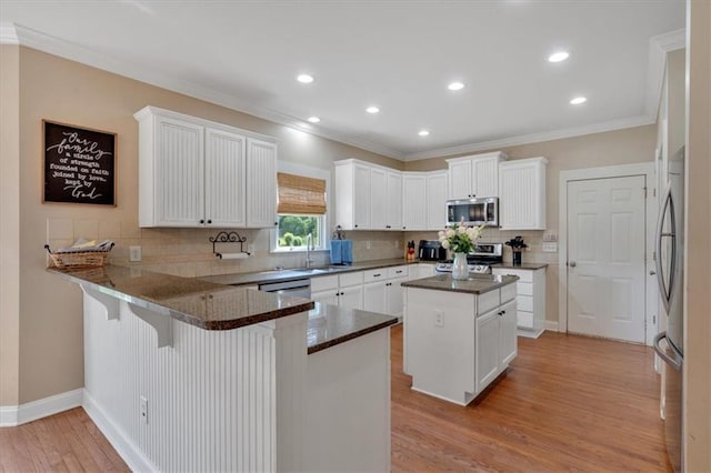 87 Washington Blvd, Dallas, GA 30132 - kitchen with appliances with stainless steel finishes, a peninsula, light wood-style flooring, decorative backsplash, and white cabinetry