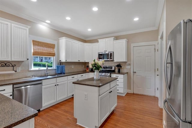 87 Washington Blvd, Dallas, GA 30132 - kitchen featuring appliances with stainless steel finishes, a sink, ornamental molding, light wood finished floors, and white cabinetry