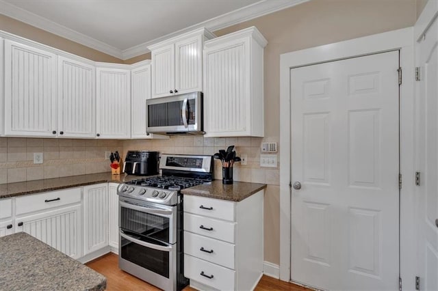 87 Washington Blvd, Dallas, GA 30132 - kitchen with appliances with stainless steel finishes, decorative backsplash, dark stone countertops, ornamental molding, and light wood-style floors