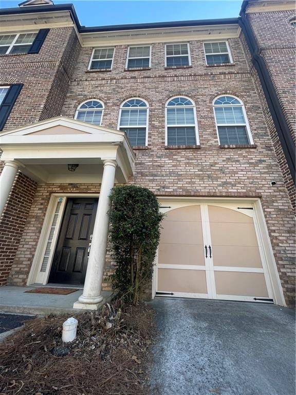 view of front of house with driveway, a garage, and brick siding