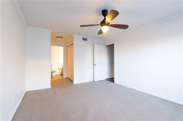 unfurnished bedroom with ensuite bath, ceiling fan, carpet floors, and ornamental molding