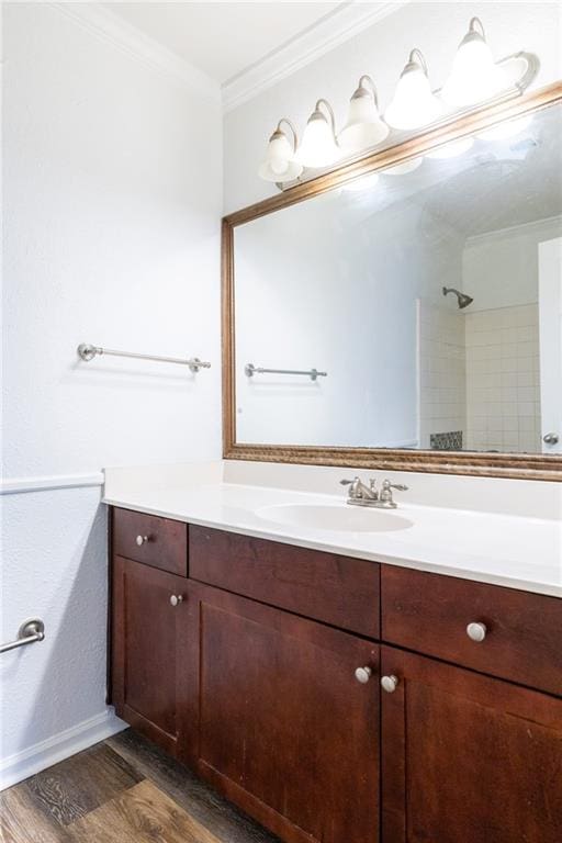 bathroom featuring tiled shower, hardwood / wood-style floors, vanity, and ornamental molding