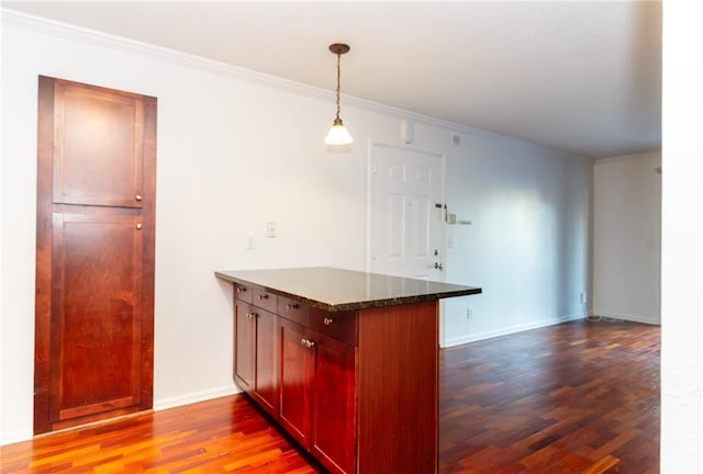 kitchen featuring dark stone counters, crown molding, decorative light fixtures, dark hardwood / wood-style flooring, and kitchen peninsula