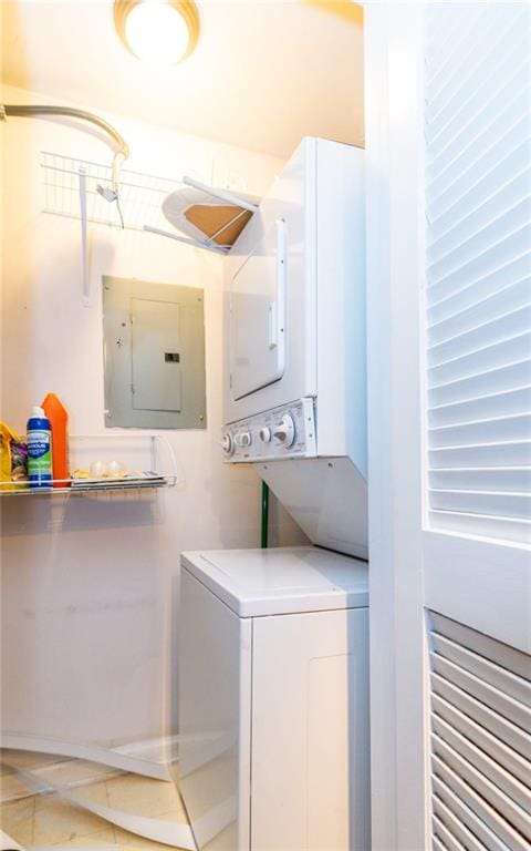 clothes washing area featuring light tile patterned flooring, electric panel, and stacked washer and clothes dryer