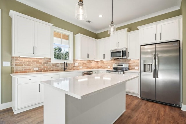 kitchen with dark wood-type flooring, a kitchen island, white cabinets, appliances with stainless steel finishes, and pendant lighting