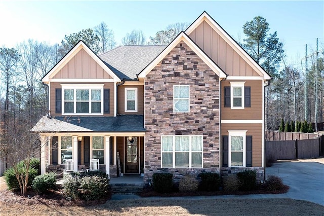 craftsman house featuring stone siding, covered porch, board and batten siding, and a shingled roof