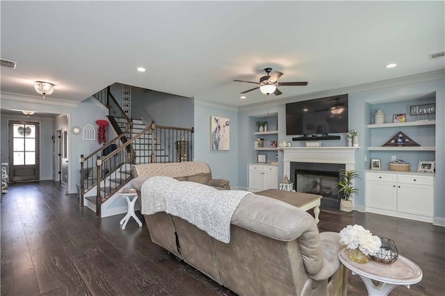living room featuring crown molding, stairway, built in shelves, wood finished floors, and ceiling fan