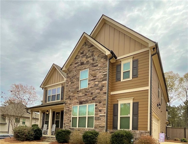 craftsman inspired home featuring stone siding, board and batten siding, and fence