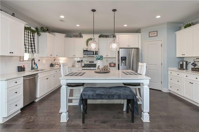 kitchen featuring backsplash, ornamental molding, white cabinets, stainless steel appliances, and a sink