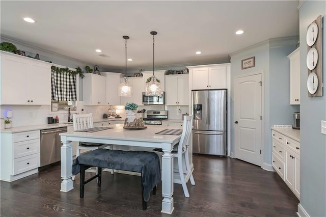 kitchen featuring backsplash, white cabinetry, a breakfast bar area, appliances with stainless steel finishes, and ornamental molding