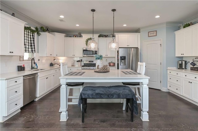 kitchen featuring crown molding, a sink, white cabinetry, appliances with stainless steel finishes, and decorative backsplash