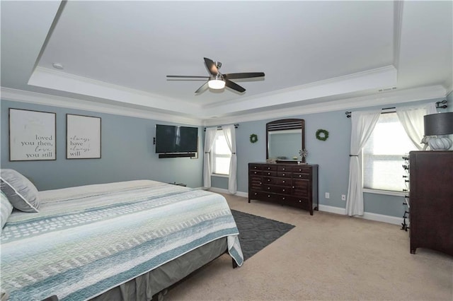 bedroom featuring ornamental molding, light carpet, a tray ceiling, and baseboards