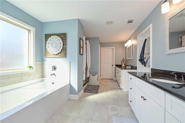 bathroom featuring a garden tub, two vanities, visible vents, and a sink