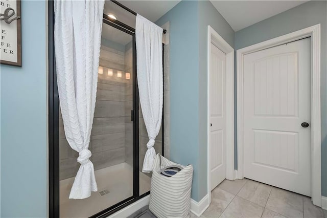 bathroom featuring tile patterned floors, a shower stall, and baseboards