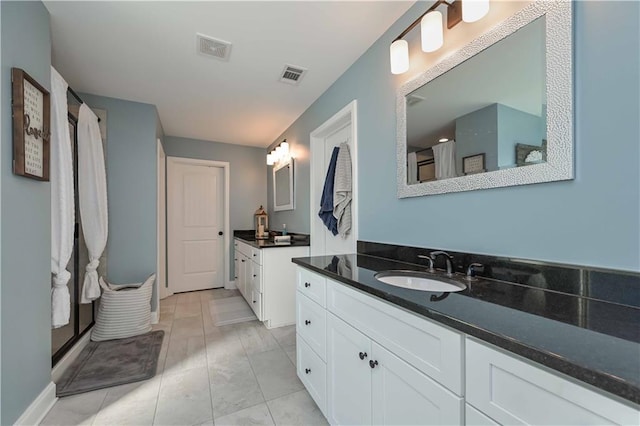 bathroom featuring visible vents, a sink, and two vanities