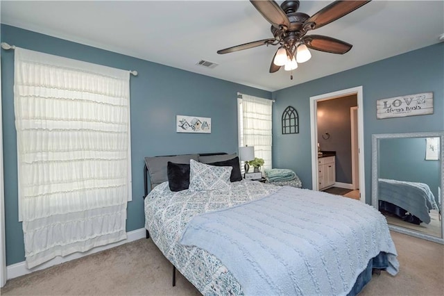 carpeted bedroom with connected bathroom, baseboards, visible vents, and a ceiling fan