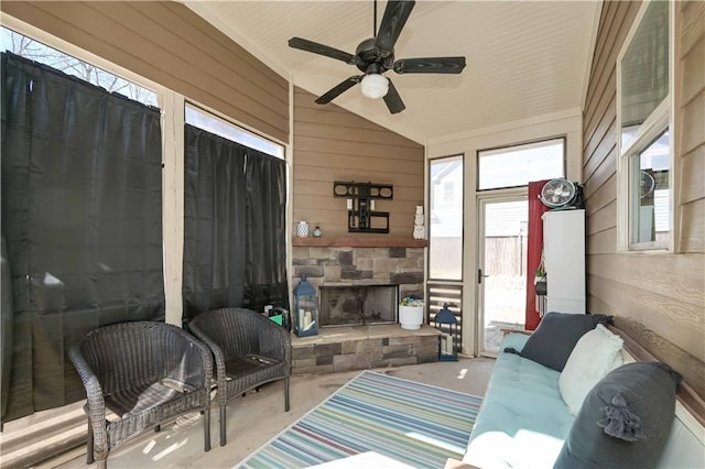 sunroom featuring ceiling fan, lofted ceiling, and an outdoor stone fireplace