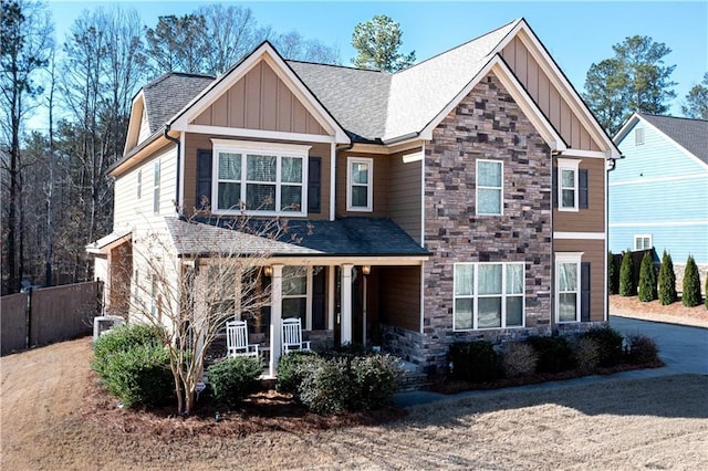 craftsman inspired home featuring a porch, fence, board and batten siding, and stone siding