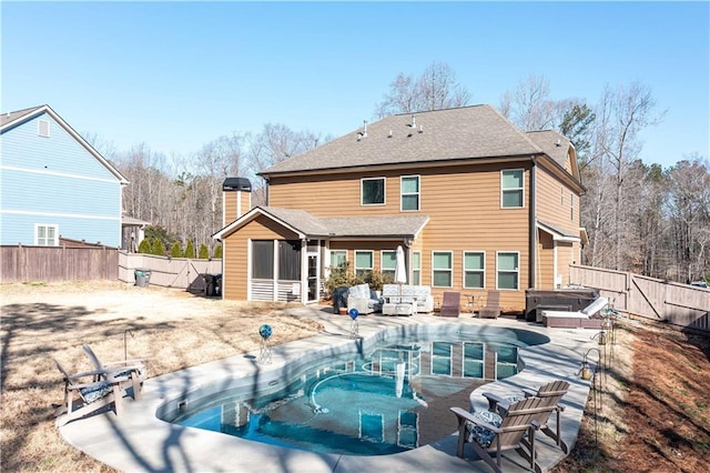 back of property with roof with shingles, a chimney, a hot tub, a fenced backyard, and a patio