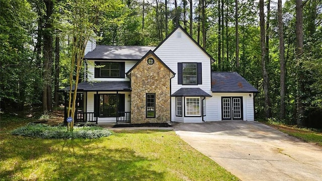 view of front of home featuring a front yard, stone siding, a chimney, concrete driveway, and a porch